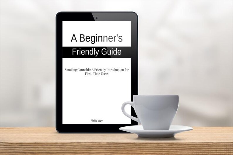 Op de afbeelding: Een zwarte tablet toont de tekst "A Beginner's Friendly Guide" met de ondertitel "Smoking Cannabis: A Friendly Introduction for First-Time Users". Een witte theekop en schotel staan op een houten oppervlak.