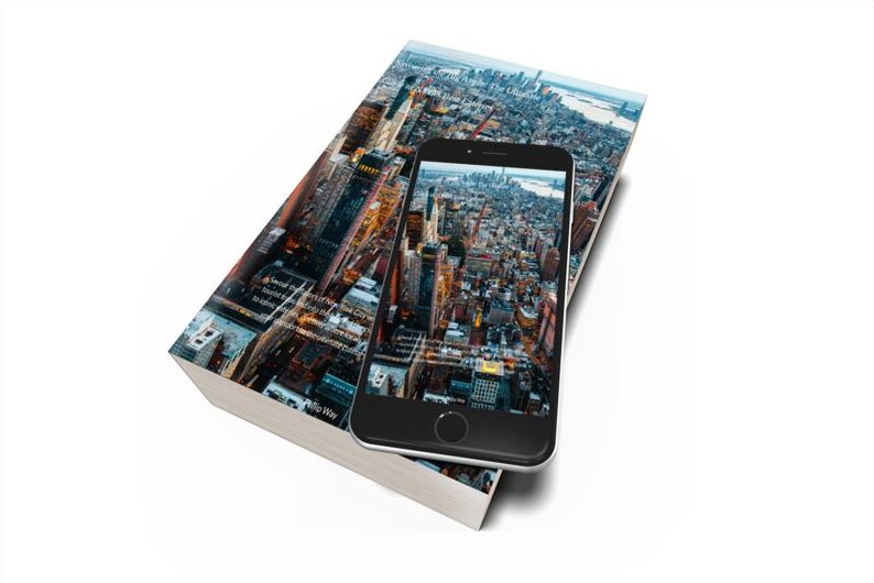 Op de afbeelding: Een hardcover boek en een smartphone met een stadsbeeld. Het boek heeft een stadsbeeld op de cover en de telefoon toont een vergelijkbaar luchtfoto. Het boek en de telefoon staan op een witte achtergrond.