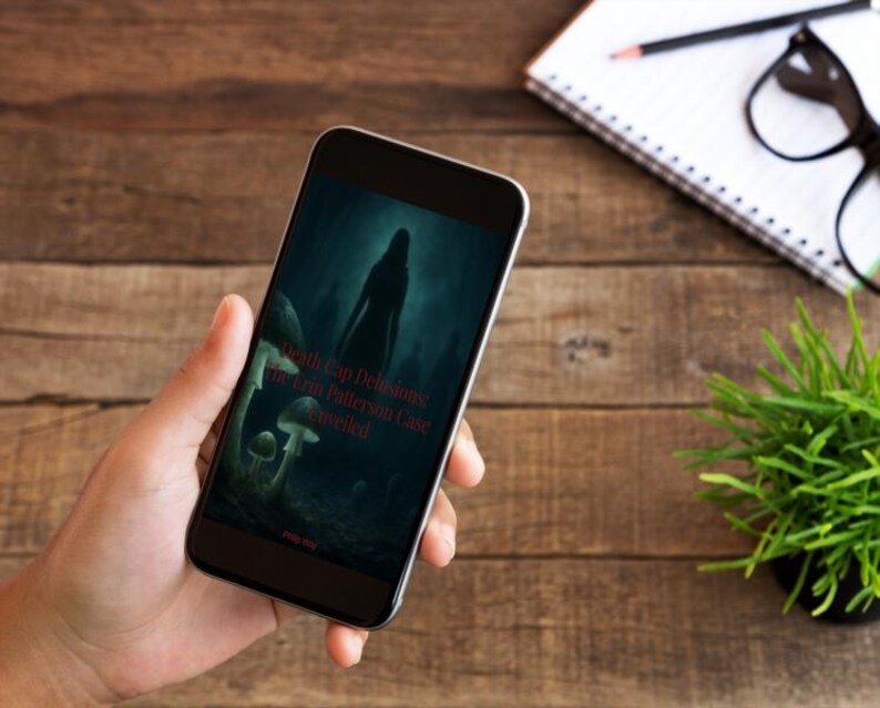 May include: A smartphone displaying a dark, atmospheric digital image of a silhouette standing in a forest with mushrooms. The text on the screen reads Death Cap Delusions: The Erin Patterson Case Unveiled in red lettering against the dark background.