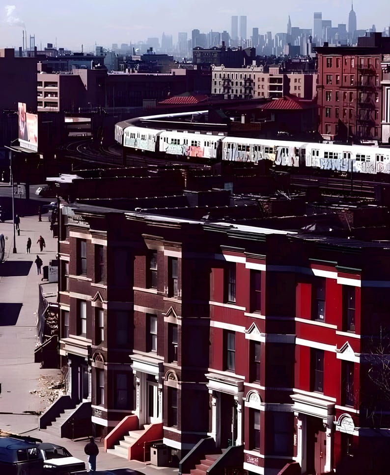 May include: Cityscape featuring a subway train curving through a neighborhood with brick buildings. The buildings are a mix of red and brown, with white trim. The distant skyline includes skyscrapers. The image has a vintage, slightly faded aesthetic.
