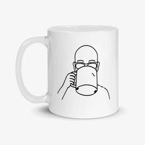 以下が含まれることがあります： 白いセラミックマグカップ。黒い線画で、マグカップから飲んでいる人が描かれています。イラストは、メガネをかけたハゲの人を描いています。マグカップは、湾曲したハンドルと円筒形をしています。