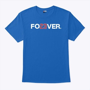 May include: A royal blue t-shirt with the text "FO23VER." printed across the chest in white and red. The shirt is a short-sleeved crew neck style.