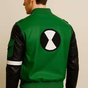 May include: Green and black bomber jacket featuring a white and black graphic on the back. The jacket has black sleeves, a green body, and a white stripe on the left sleeve. It has a ribbed collar and cuffs.
