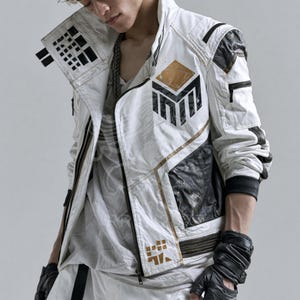 May include: A white jacket with black and gold geometric accents, featuring a high collar, a front zipper, and a prominent black and gold logo on the chest. The jacket includes black textured panels on the sides and shoulders with black zippers.