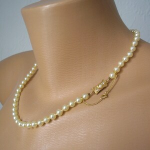 May include: A classic pearl necklace with a gold clasp. The necklace is made of white pearls and has a simple design.