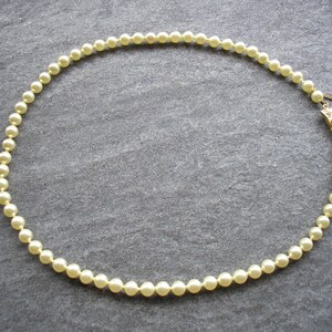 May include: A strand of white pearl beads with a gold clasp.