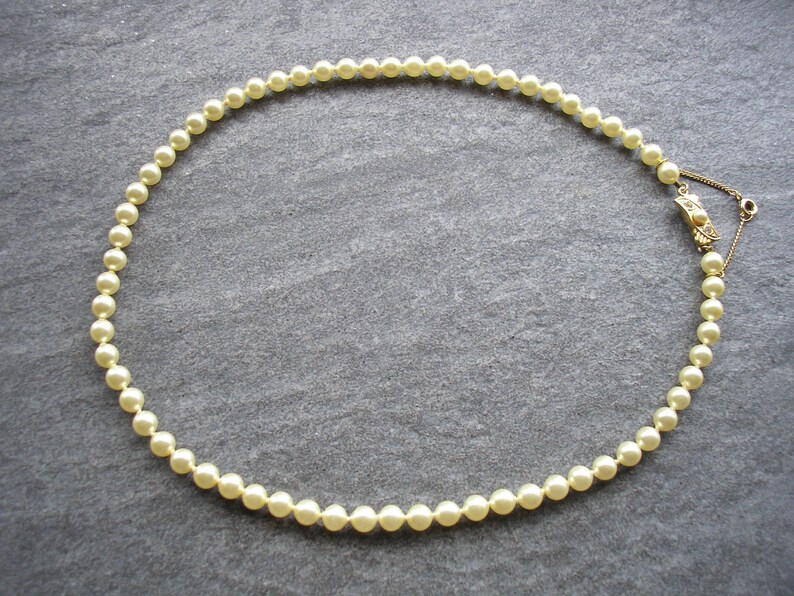 May include: A strand of white pearl beads with a gold clasp.