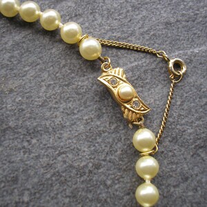 May include: A gold chain necklace with a pearl clasp and a strand of cream-colored pearls.