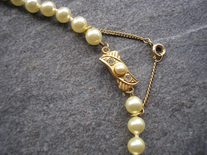 May include: A gold chain necklace with a pearl clasp and a strand of cream-colored pearls.