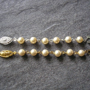 May include: Two pearl necklaces with gold and silver clasps. Each necklace has a series of white pearls connected by a thin metal chain.