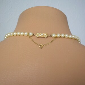 May include: A gold chain necklace with a gold clasp and a row of white pearls.