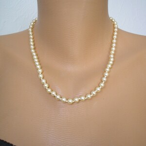 May include: A simple pearl necklace with a classic design. The necklace is made of white pearls and is strung on a silver chain.