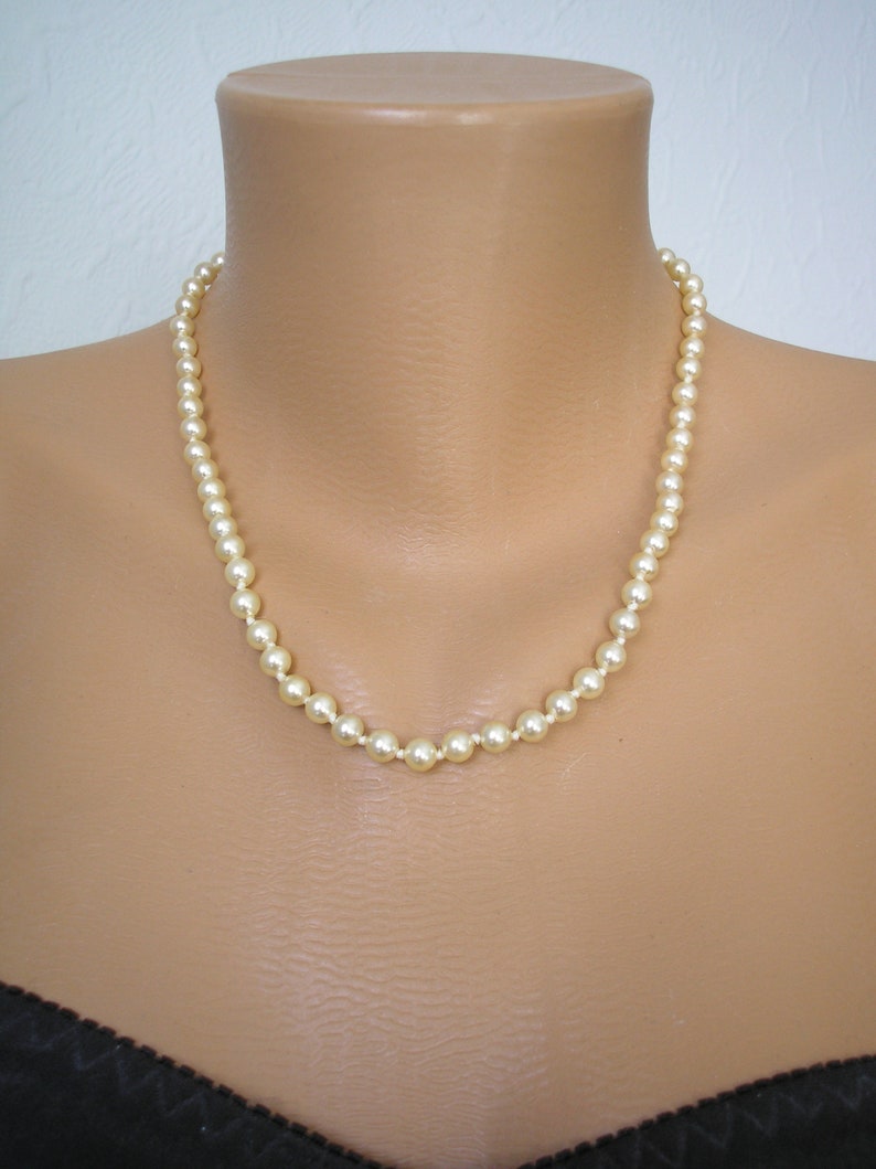 May include: A simple pearl necklace with a classic design. The necklace is made of white pearls and is strung on a silver chain.