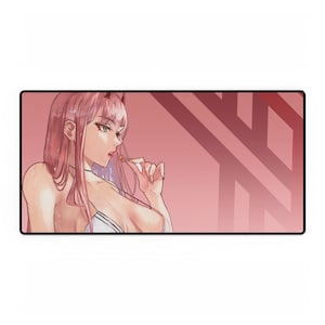 May include: A rectangular desk mat featuring an anime-style illustration of a character with long pink hair and red horns. The character is holding a small round lollipop near their mouth. The background is a solid dusty rose with dark red lines.