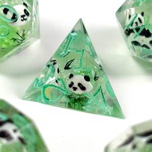May include: A set of handmade, clear resin dice with a panda bear design. The dice are a light green color and have a panda bear encased inside. The dice are for tabletop games.