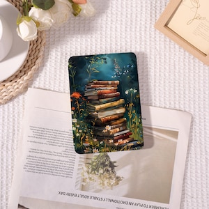 May include: A rectangular sticker featuring a stack of books with a floral and foliage background. The books are various colors, and the background is a dark teal with white flowers and butterflies. The sticker is on top of a newspaper.