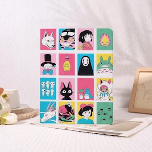 May include: A colorful notebook featuring a grid of cartoon character illustrations. The images include a white wolf, a cat-like creature, a girl in a pink jacket, and a flame. Other characters include a smiling figure in a top hat and a black cat.