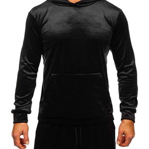 Puede incluir: Sudadera con capucha de terciopelo negro con bolsillo de canguro y capucha con cordón. La parte superior de manga larga forma parte de un conjunto a juego. La tela tiene un aspecto suave y brillante.