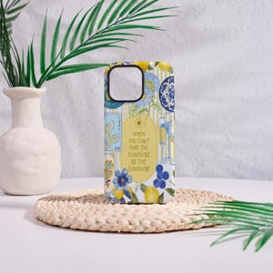 May include: A phone case with a colorful floral and lemon design. The case features blue flowers, yellow lemons, and the text "When you can't find the sunshine be the sunshine."