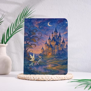 Könnte beinhalten: Ein rechteckiges Notizbuch mit einer Fantasy-Illustration einer steinernen Burg mit blauen Türmen unter einem sternenklaren Nachthimmel mit einer Mondsichel. Ein gewundener Pfad führt zur Burg und kleine geflügelte Wesen fliegen über einen Bach.