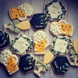 May include: A set of 10 decorated sugar cookies with various designs, including beer mugs, champagne flutes, and floral wreaths. The cookies are decorated with white, yellow, green, and blue icing. The cookies feature the text "Haley & Leo" and the date "9.12.20".