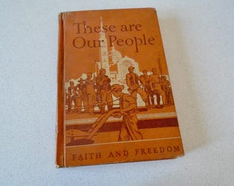 Pode incluir: Um livro vintage intitulado "These are Our People" com uma capa laranja. A capa apresenta ilustrações de pessoas e uma igreja, com as palavras "Faith and Freedom" na parte inferior. O livro está desgastado.