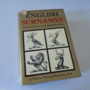 May include: A vintage book titled "English Surnames" with the subtitle "Their Sources and Significations." The cover is tan with black and red text and features four black and white illustrations of heraldic symbols.