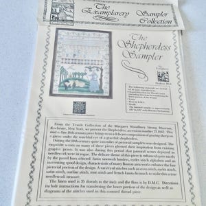 May include: A cross-stitch sampler kit titled "The Shepherdess Sampler" from The Exemplarery Sampler Collection. The kit includes linen, floss, and needle. The packaging features a detailed image of the finished sampler with a pastoral scene.