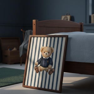 May include: A framed print featuring a teddy bear wearing a blue sweater and khaki pants, set against a backdrop of blue and white vertical stripes. The artwork is displayed in a room with a bed and wooden furniture.