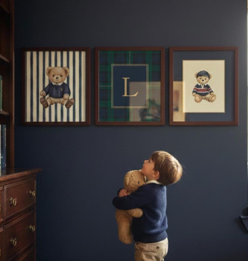 May include: Three framed pictures with teddy bear illustrations hang on a dark blue wall. The frames are brown. One picture has a teddy bear on a striped background, another has a plaid pattern with the letter "L", and the third has a teddy bear in a sailor outfit.