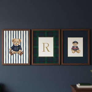 May include: Three framed prints featuring teddy bear illustrations. One print has a teddy bear in a blue sweater against a striped background. Another has a letter "R" on a plaid background. The third print has a teddy bear in a striped shirt.