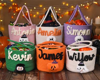 May include: Six colorful, handmade Halloween treat baskets. Each basket is a different color, with a name on the front. The baskets are filled with candy and decorated with Halloween-themed characters, including ghosts and pumpkins.