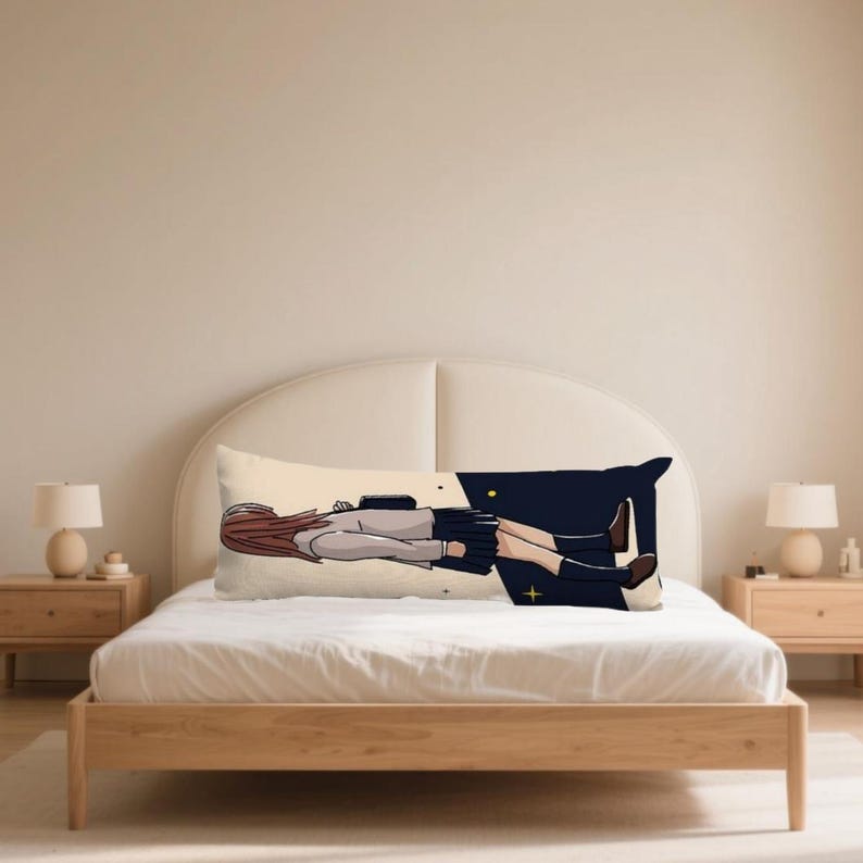 May include: A rectangular body pillow with an anime-style illustration of a person in a school uniform. The pillow has a cream-coloured background with a dark blue and black design on the right. The person has brown hair and wears a grey top and a black skirt.