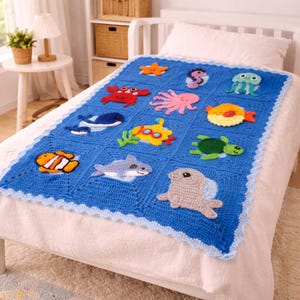 May include: A blue crochet blanket featuring various sea creatures, including a starfish, crab, octopus, whale, submarine, turtle, clownfish, shark, and seal. The blanket has a scalloped edge and is displayed on a white bed.