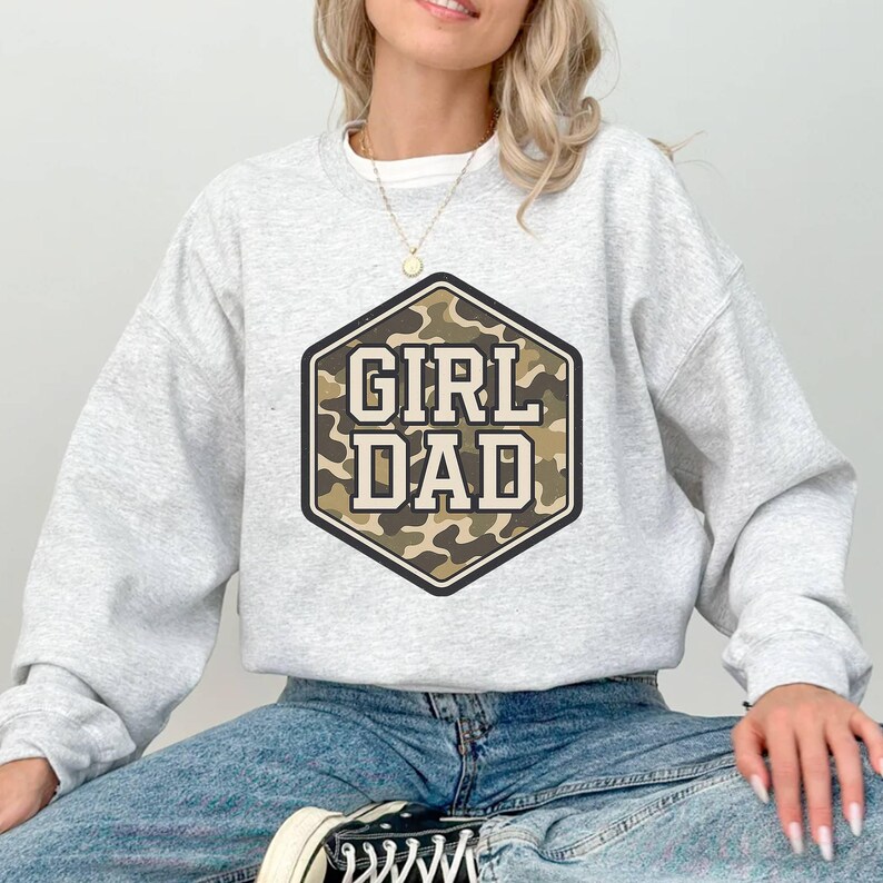 a woman sitting on the ground wearing a grey sweatshirt
