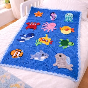 May include: A blue crochet blanket featuring various sea creatures, including a starfish, seahorse, crab, octopus, and fish. The blanket has a scalloped edge and is displayed on a bed.