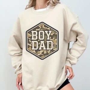 a woman wearing a sweatshirt that says boy dad