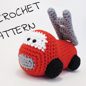 May include: A crocheted fire engine toy in red, white, grey, and black. The toy features a ladder and the text "CROCHET PATTERN". The toy is made of yarn and has black wheels. A handmade item.