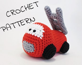 May include: A handmade crochet fire truck toy in red, white, gray, and black. The toy has a ladder on top and the text "CROCHET PATTERN" in black. The toy is made of yarn and has black wheels.