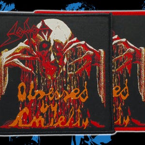 May include: Two black patches with a red border featuring a skull design with dripping red and orange accents. The word "Sodom" is at the top, and "Obsessed by Anarchy" is written in orange below the skull. The patches are likely for a jacket or bag.