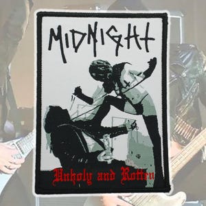 May include: A rectangular patch with a black border featuring a black and white illustration. The image depicts two figures, one standing over the other. The word "MIDNIGHT" is at the top, and "Unholy and Rotten" is at the bottom.