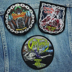 Può includere: Tre toppe in tessuto ricamato con illustrazioni di gruppi heavy metal. Una toppa circolare mostra Monstrosity Imperial Doom, una toppa rettangolare mostra Cannibal Corpse Eaten Back to Life e una toppa circolare raffigura Obituary Slowly We Rot.