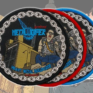Pode incluir: Três patches redondos bordados com fundo preto e borda de corrente. Os patches exibem um gráfico de um homem em uma escavadeira com o texto "METALWOPER" e "HEAVY METAL BULLDOZER". Os patches têm bordas vermelhas e azuis.