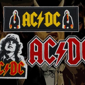 Puede incluir: Parches bordados de AC/DC. Los parches muestran el logotipo de la banda en amarillo y rojo, una silueta de una figura y un retrato de un hombre con sombrero. Los parches son en blanco y negro.
