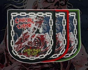 Puede incluir: Tres parches rectangulares bordados con la portada del álbum Eaten Back to Life de Cannibal Corpse. Cada parche muestra una figura zombi, un borde de cadena plateada y texto rojo. Los bordes están cosidos en negro, rojo y verde.