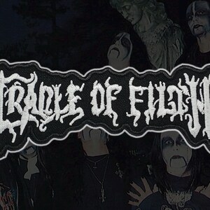 Op de afbeelding: Een zwart-wit geborduurde patch met de bandnaam "Cradle of Filth" in gotische letters. De patch heeft een witte rand en een donkere achtergrond met bandleden.