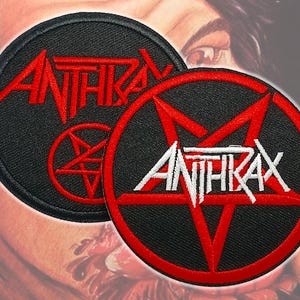 May include: Two round black patches with the word "ANTHRAX" in red and white. One patch has the word in red, the other in white. Both patches feature a red pentagram design. The patches are likely for clothing or accessories.