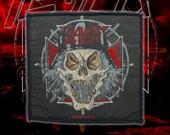 May include: A square black embroidered patch featuring a central skull graphic with wild hair, positioned over a red and white cross emblem. The word SLAYER is stitched in red at the top, and the text 2007 SLAYER is visible at the bottom edge.