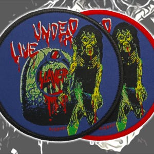 May include: Two circular embroidered patches featuring a blue background with a graphic of a zombie and a tombstone. The text "LIVE UNDEAD" appears in red dripping letters at the top, and the word "SLAYER" is printed in red on the tombstone.