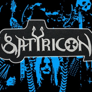 Peut inclure: Écusson noir avec le mot "SATYRICON" brodé en blanc, orné d'un symbole de trident et d'une croix. L'écusson a une forme unique et est placé sur un fond noir avec des éléments graphiques bleus, probablement un logo de groupe.